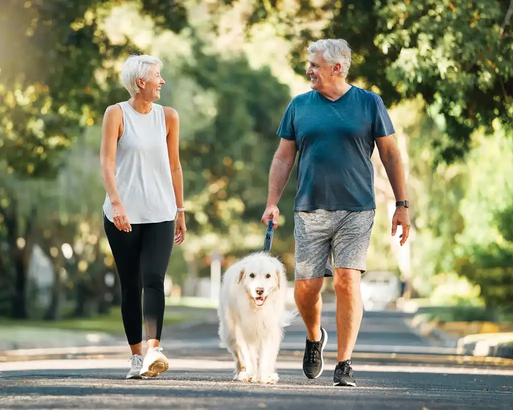 older couple walking their dog outside