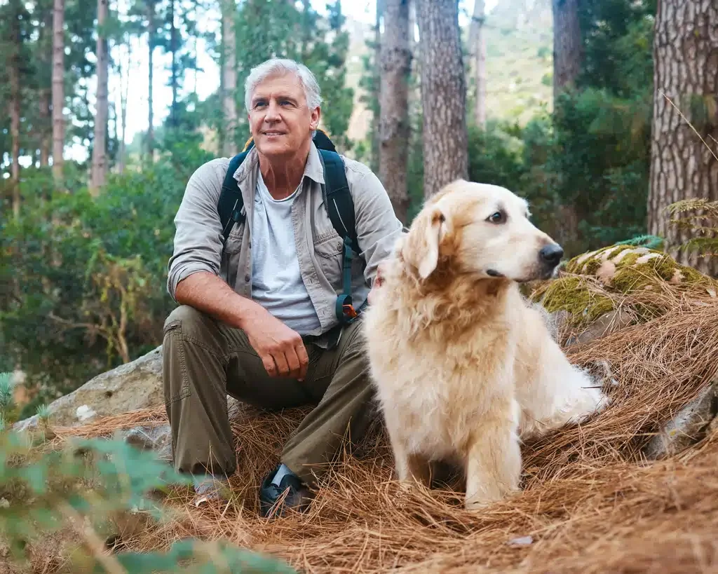 older man in the forest with hid golden retriever